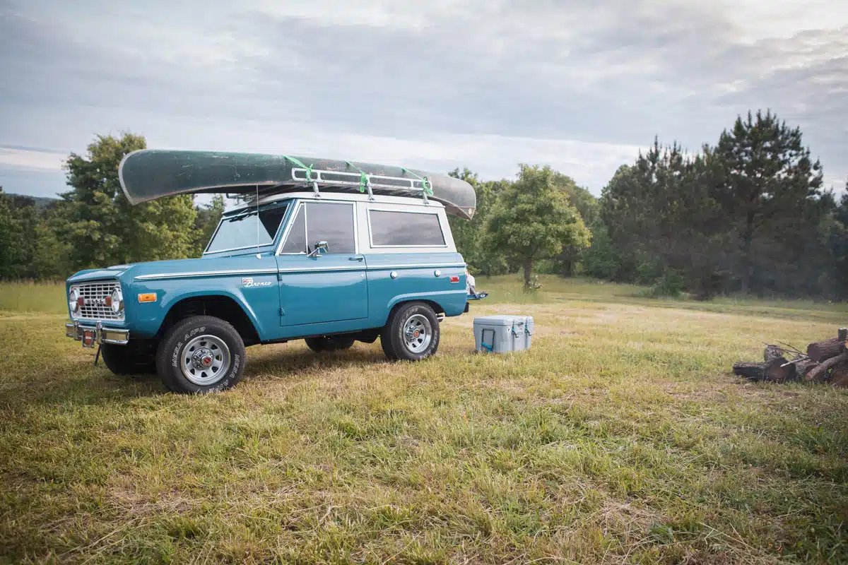 A classic first generation Ford Bronco parked in a field