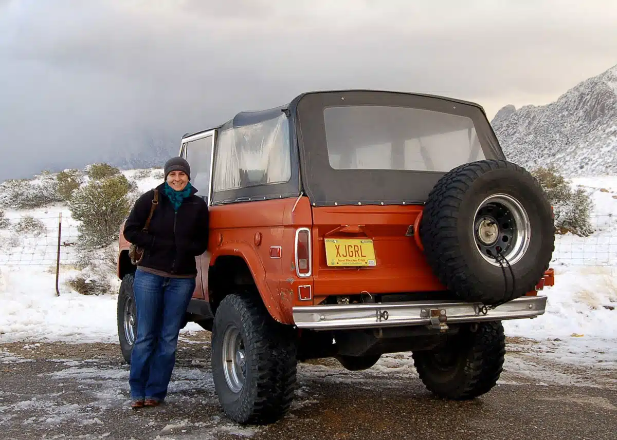 Classic Ford Bronco on a snowy road with snow-covered mountains in the background