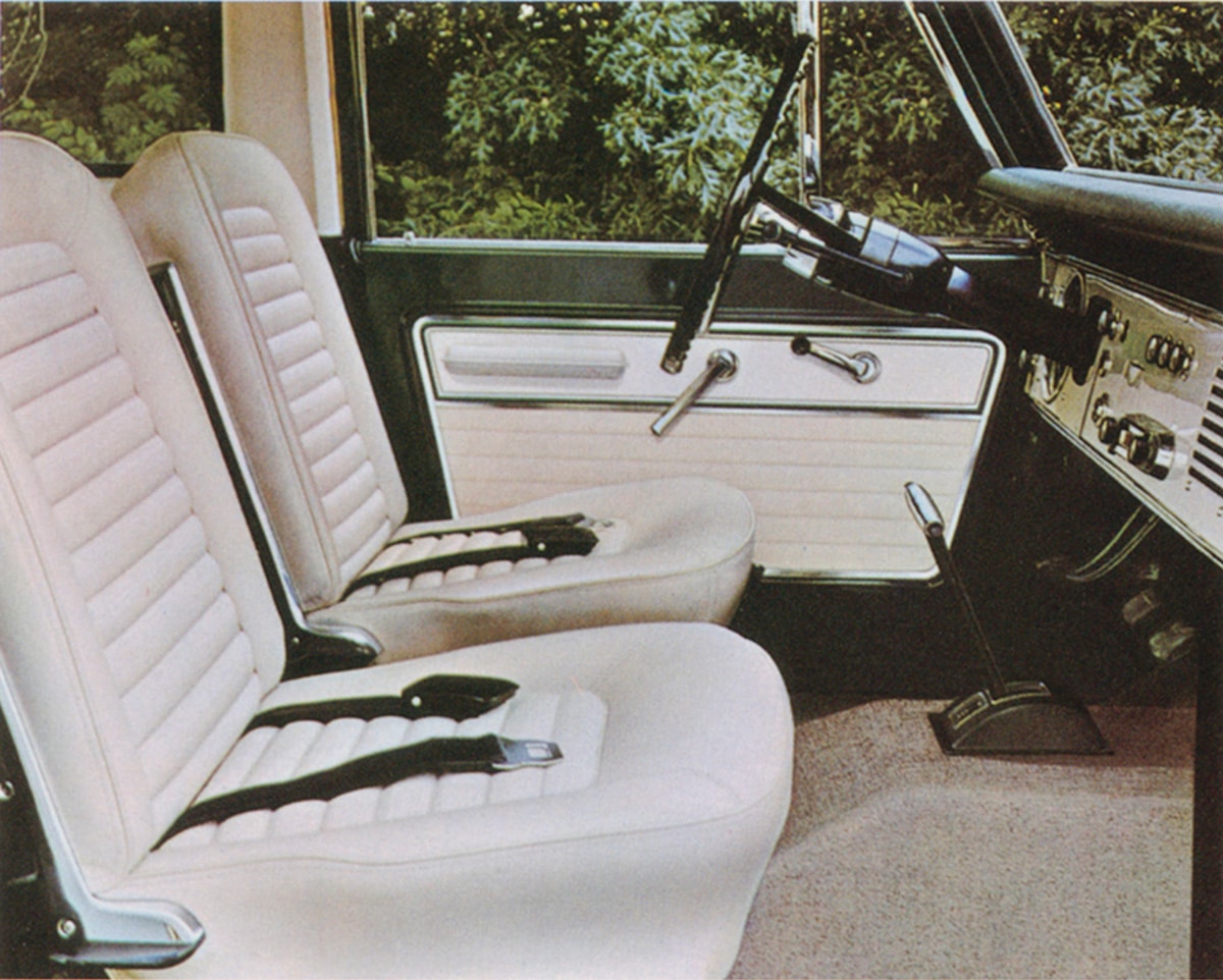 Interior view of a vintage vehicle with white bucket seats and a classic dashboard design